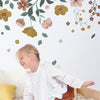 Organisch kinderbehang met zachte roze en okergele bloemen en groene bladeren, geschikt voor kinderkamer en kinderinterieur, . - 2.48 x 2 M - Capucine Behangwand | Lilipinso - behang, behangpaneel, bloemen, bloemen en bladeren, Capucine, kinderkamer, kinderkamer behang, lilipinso - Casa Mini