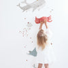 Kind met witte jurk die rood rubberen krabfiguur vasthoudt, voor organische muursticker met grijze walvis, blauwe. - Muursticker | Ocean Field XL - Default Title - kinderkamer, kwal, lilipinso, Muursticker, Oceaan dieren, ocean field, vliesbehang, walvis - Casa Mini